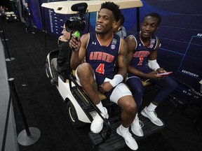 Auburn's Malik Dunbar and Jared Harper get a ride in a gold cart after a practice session for the semifinals of the Final Four NCAA college basketball tournament, Thursday, April 4, 2019, in Minneapolis.