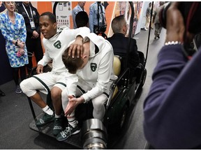 Michigan State's Cassius Winston, left, and Matt McQuaid react as they take a cart back to the locker room after the team's 61-51 loss to Texas Tech in the semifinals of the Final Four NCAA college basketball tournament, Saturday, April 6, 2019, in Minneapolis.