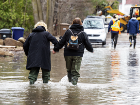 Residents wade through a flooded street, April 25, 2019 in Laval, Que.