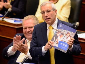 Ontario Premier Doug Ford applauds as Finance Minister Vic Fedeli presents the 2019 budget in the provincial legislature in Toronto on April 11, 2019.