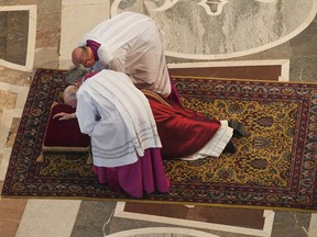 Pope Francis gets assistance as he lies down in prayer prior to celebrate Mass for the Passion of Christ, in St. Peter's Basilica at the Vatican, Friday, April 19, 2019. Pope Francis began the Good Friday service at the Vatican with the Passion of Christ Mass and hours later will go to the ancient Colosseum in Rome for the traditional Way of the Cross procession.