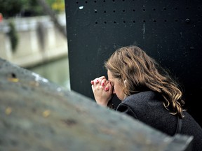 A woman sits in despair near the Notre Dame cathedral after the fire in Paris, Tuesday, April 16, 2019.