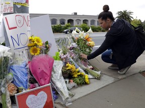 A woman leaves flowers on a growing memorial across the street from the Chabad of Poway synagogue in Poway, Calif., on Monday, April 29, 2019. A gunman opened fire on Saturday, April 27 as dozens of people were worshipping exactly six months after a mass shooting in a Pittsburgh synagogue.