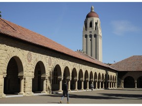 FILE- In this March 14, 2019, file photo, people walk on the Stanford University campus beneath Hoover Tower in Stanford, Calif. Stanford University has expelled a student who lied about her sailing credentials in her application, which was linked to a foundation at the center of the college-admission bribery scandal. The university quietly announced it had rescinded the student's admission in a short statement posted on its website April 2, 2019, after determining "some of the material in the student's application is false."