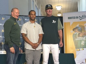 Oakland Athletics designated hitter Khris Davis, center, poses with general manager David Forst, left, and manager Bob Melvin, right, during a news conference about his contract extension Friday, April 19 2019, in Oakland, Calif.