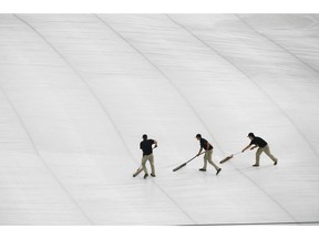 Atlanta Braves grounds crew roll water off a tarp covering the infield before a delay in the start of a baseball game against the New York Mets was announced Sunday, April 4, 2019, in Atlanta.