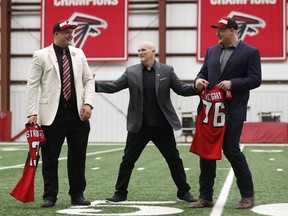 Atlanta Falcons head football coach Dan Quinn, center, arranges NFL football first-round-draft picks Chris Lindstrom, left, of Boston College, and Kaleb McGary, from Washington, for a photo Friday, April 26, 2019, in Flowery Branch, Ga. Lindstrom and McGary are both offensive linemen.
