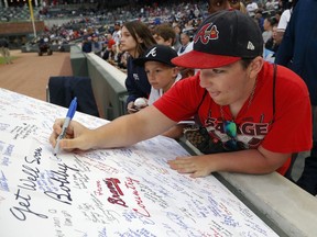 A fan signs a get well card for former Braves manager Bobby Cox who reportedly is being hospitalized after suffering a stroke Thursday, April 4, 2019, in Atlanta.