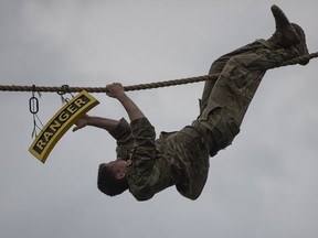 U.S. Army Lt. Alastair Keys, of the 173rd Airborne Brigade Combat Team, touches a Ranger Tab as he climbs across a rope stretched high over Victory Pond during the combat water skills portion of the Best Ranger competition Sunday, April 14, 2019, at Fort Benning, Ga.