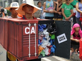 Filipino environmental activists wear mock container vans filled with garbage to symbolize the 50 containers of waste that were shipped from Canada to the Philippines two years ago, outside the Canadian embassy south of Manila, Philippines on May 7, 2015.
