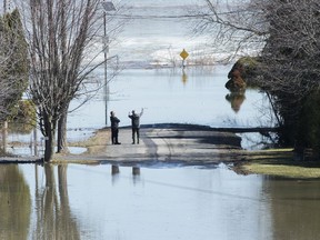 Two men look out towards the Ottawa River on a residential street surrounded by floodwaters in the town of Rigaud, Que, west of Montreal, Monday, April 22, 2019.