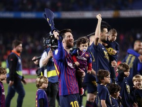 Barcelona forward Lionel Messi, left, and Barcelona midfielder Sergio Busquets, with their children, celebrate winning the Spanish League title, at the end of the Spanish La Liga soccer match between FC Barcelona and Levante at the Camp Nou stadium in Barcelona, Spain, Saturday, April 27, 2019. Barcelona clinched the Spanish La Liga title, with three matches to spare, after it defeated Levante 1-0.