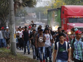 FILE - In this April 10, 2019 photo, migrants walk along a highway as a caravan of several hundred people sets off from San Pedro Sula, Honduras in hopes of reaching the distant United States. Calls for a new migrant caravan departing April 30 went largely unheeded as a relatively small group departed from Honduras one week after a raid by Mexican police resulted in hundreds of detentions and the dissolution of a previous caravan.