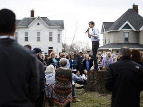 In this Friday, April 5, 2019 photo, people listen as Democratic presidential candidate and former Texas Representative Beto O'Rourke stands on a stump to give his speech at the Mowry Irvine Mansion during a swing though Iowa in Marshalltown, Iowa.