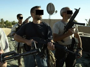 Iraqi and foreign mercenary members of a private security company stand on the rooftop of a house in Baghdad on 18 September 2007.
