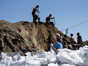 Canadian Forces members stand on a mountain of sand as they make sandbags to protect homes on Voisine Road in Clarence-Rockland, east of Ottawa, as flooding continues to affect the region on Sunday, April 28, 2019. Were it not for volunteers and the military as water levels climbed over the weekend, victims of this year's devastating spring flooding in Eastern Canada say many more homes would be lost to the disaster.