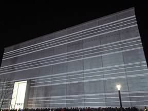 People stand in front of the new Bauhaus Museum building during a light installation performance at the official opening by the Klassik Stiftung Weimar in Weimar, Germany, Friday, April 5, 2019. The museum, designed by Berlin-based Heike Hanada, will focus on the early Bauhaus that was founded in Weimar in 1919 and stayed there until 1925.