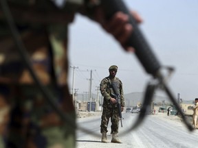 in this Sunday, April 28, 2019 photo, Afghan National Army soldiers stand guard at a checkpoint on the Jalalabad-Kabul road, on the outskirts of Kabul, Afghanistan. President Ashraf Ghani is hosting a grand council of some 2,500 prominent figures on Monday, to agree on a shared approach to peace talks with the Taliban. But the gathering instead looks to further aggravate divisions within the U.S.-backed government, even as America makes progress with the insurgents in direct talks aimed at ending the 18-year war.