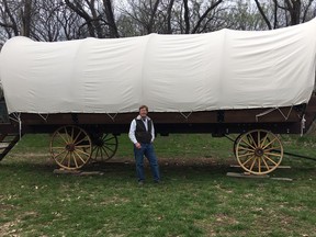 In this April, 11, 2019 photo, Dennis Steinman stands in front of his first covered wagon outside his home in rural Douglas County, Kansas. Dennis and Donna Steinman have built the first of what they hope will be many 26-by-10-foot canvas-covered wagons. Their PlainsCraft Conestoga Wagons are more like the Winnebago of covered wagons; they're intended for those drawn to glamorous camping, or glamping.