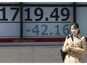 A woman stands by an electronic stock board of a securities firm in Tokyo, Tuesday, April 9, 2019. Asian markets have followed Wall Street higher as investors watched for Brexit developments and corporate earnings. Benchmarks in Shanghai, Hong Kong and Seoul gained, while Tokyo was flat.