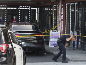 FILE - In this March 31, 2019, file photo, a Los Angeles Police officer walks under a yellow tape by the Marathon Clothing store of rapper Nipsey Hussle in Los Angeles. Authorities say a man arrested on a parole violation after being wounded at this location in the Los Angeles shooting that killed Nipsey Hussle has been released from jail. Kerry Lathan had been in custody since being shot March 31 along with the rapper. KABC-TV reports Lathan walked out of LA's Men's Central Jail on Saturday, April 20. Lathan's lawyer says, her client just happened to be in the area when Hussle was gunned down.