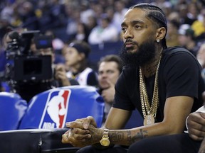 FILE - In this March 29, 2018, file photo, rapper Nipsey Hussle watches an NBA basketball game between the Golden State Warriors and the Milwaukee Bucks in Oakland, Calif. Grammy-nominated and widely respected West Coast rapper Nipsey Hussle has been shot and killed outside his Los Angeles clothing store, Los Angeles Mayor Eric Garcetti said Sunday, March 31, 2019. He was 33.
