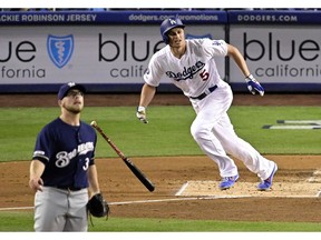 Los Angeles Dodgers' Corey Seager heads to first on his home run off Milwaukee Brewers starting pitcher Corbin Burnes, left, during the first inning of a baseball game Friday, April 12, 2019, in Los Angeles.