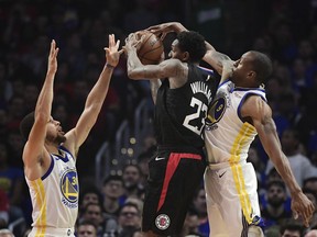 Los Angeles Clippers guard Lou Williams, center, tries to shoot as Golden State Warriors guard Stephen Curry, left, and guard Andre Iguodala defend during the first half in Game 3 of a first-round NBA basketball playoff series Thursday, April 18, 2019, in Los Angeles.