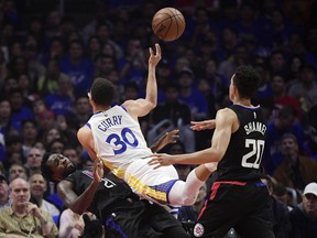 Golden State Warriors guard Stephen Curry, center, runs into Los Angeles Clippers guard Patrick Beverley, left, as he shoots while guard Landry Shamet watches during the first half in Game 4 of a first-round NBA basketball playoff series Sunday, April 21, 2019, in Los Angeles.