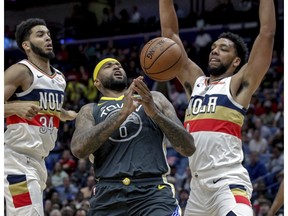 Golden State Warriors center DeMarcus Cousins (0) loses control of the ball while driving to the basket against New Orleans Pelicans guard Kenrich Williams (34) and center Jahlil Okafor (8) in the first half of an NBA basketball game in New Orleans, Tuesday, April 9, 2019.