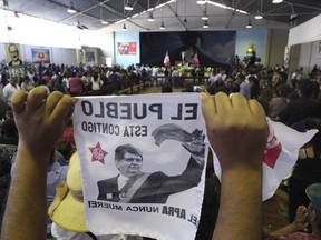 A supporter holds up an image of Peru's late President Alan Garcia on the second day of his wake at his party's headquarters in Lima, Peru, Thursday, April 18, 2019. Garcia shot himself in the head and died Wednesday as officers waited to arrest him in a massive graft probe that has put the country's most prominent politicians behind bars and provoked a reckoning over corruption.