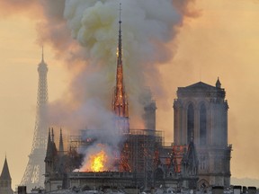 FILE - In this file photo dated Monday, April 15, 2019, with the Eiffel Tower behind, left, flames and smoke rise from the blaze at Notre Dame Cathedral in Paris that destroyed its spire and its roof but spared its twin medieval bell towers, and prompted a frantic rescue effort to save its most precious artefacts.  The recent devastating Notre Dame fire in Paris was a warning bell that all of Europe needs to hear, since so many monuments and palaces across the continent are in need of better upkeep according to European officials.  "We are so used to our outstanding cultural heritage in Europe that we tend to forget that it needs constant care and attention," Tibor Navracsics, the European Union's top culture official, told The Associated Press.