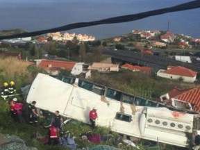 In this image from video, emergency services attend the scene after a tour bus crashed at Canico, on Portugal's Madeira Island, Wednesday April 17, 2019.  Some 28 people are reported to have died in the crash, most of them German tourists, local mayor Filipe Sousa told TV news. (TVI via AP)