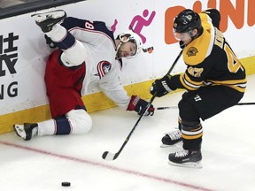 Columbus Blue Jackets right wing Oliver Bjorkstrand, left, slams into the boards after being upended by Boston Bruins defenseman Torey Krug, right, while chasing the puck during the first period of Game 1 of an NHL hockey second-round playoff series, Thursday, April 25, 2019, in Boston.