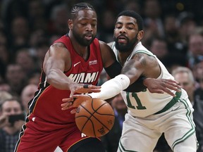 Boston Celtics guard Kyrie Irving (11) reaches in on a steal-attempt against Miami Heat guard Dwyane Wade (3) during the first quarter of an NBA basketball game in Boston, Monday, April 1, 2019.