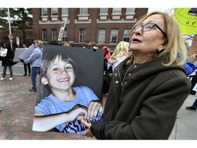 Barbara Cowley, of Boston, carries a photo of her son Justin Cowley-Kerner, who was 30 when he died of an opiate overdose in 2015, outside the Arthur M. Sackler Museum at Harvard University, Friday, April 12, 2019, in Cambridge, Mass. Cowley took part in a demonstration by parents who have lost a child to opioid overdose, campaigning for the removal of the Sackler family name from the building at Harvard.