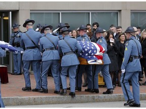 Hillary Campbell, right,  the wife of Maine State Police detective Ben Campbell, holds a cloth to her face as his casket is carried into the Cross Insurance Arena during his funeral procession, Tuesday, April 9, 2019, in Portland, Maine.   Campbell was helping a motorist last week when he was struck and killed by a wheel that had dislodged from a logging truck.