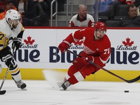 Pittsburgh Penguins right wing Bryan Rust (17) and Detroit Red Wings center Dylan Larkin (71) chase the puck during the first period of an NHL hockey game, Tuesday, April 2, 2019, in Detroit.