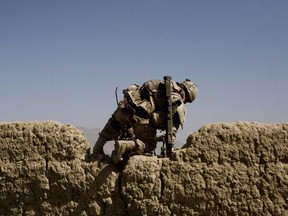 A Canadian soldier with 1st RCR Battle Group, the Royal Canadian Regiment, climbs over a wall as he patrols with his unit to find Improvised Explosive Devices or IEDs in the Panjwayi district, south west of Kandahar, Afghanistan on June 6, 2010.