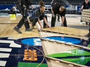 U.S. Bank Stadium operations worker Jaimyan Daveiga, center, helps install the court for the NCAA Final Four college basketball tournament in Minneapolis, Friday, March 29, 2019.