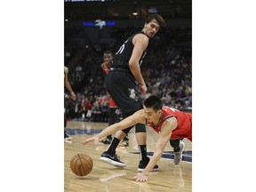 Toronto Raptors' Jeremy Lin falls to get the ball behind Minnesota Timberwolves' Dario Saric in the first half of an NBA basketball game Tuesday April 9, 2019, in Minneapolis.