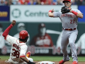 Cincinnati Reds' Derek Dietrich (22) forces out St. Louis Cardinals' Jose Martinez (38) and completes a double play by getting Yadier Molina at first in the second inning of a baseball game, Saturday, April 27, 2019 at Busch Stadium in St. Louis.