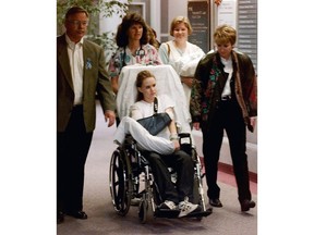 FILE - In this May 1, 1999, file photo, Kacey Ruegsegger, 17, is wheeled from a Denver hospital by Patty Anderson, center, after being released. Walking beside her are her parents Greg, left, and Darcy, right. Ruegsegger Johnson survived a shotgun blast during the 1999 shootings at Colorado's Columbine High School that left 12 students, one teacher, and both gunmen dead.