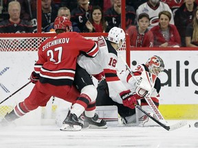 New Jersey Devils goalie Cory Schneider defends the goal while Devils' Steven Santini (16) defends against Carolina Hurricanes Andrei Svechnikov (37), of Russia, during the first period of an NHL hockey game in Raleigh, N.C., Thursday, April 4, 2019.