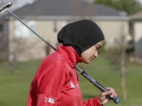 In this April 10, 2019 photo, Noor Ahmed, a member of the Nebraska NCAA college golf team, carries her putter during practice in Lincoln, Neb. Ahmed is the only golfer at the college level or higher known to wear a hijab while competing. She hopes Muslim girls are watching her and encouraged to chase their dreams in environments where they might encounter fear, uncertainty and hostility.