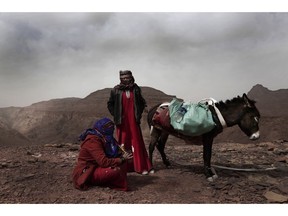 In this March 30, 2019 photo, Umm Yasser, the first Bedouin female guide from the Hamada tribe, looks at Umm Soliman as she plays the flute, near Wadi Sahw, Abu Zenima, in South Sinai, Egypt. Umm Yasser is breaking new ground among the deeply conservative Bedouin of Egypt's Sinai Peninsula. Women among the Bedouin almost never work outside the home, and even more rarely do they interact with outsiders. But Umm Yasser is one of four women from the community who for the first time are working as tour guides.