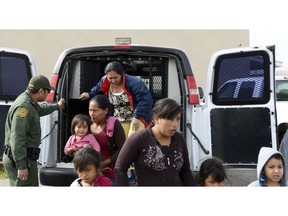 In this Friday, April 12, 2019 photo, a U.S. Border Patrol agent helps migrants out of a van at the Gospel Rescue Mission in Las Cruces, N.M. The U.S. Border Patrol agents dropped off asylum-seeking migrants in New Mexico's second most populous city for the second day in a row Saturday, April 13, 2019 prompting Las Cruces city officials to appeal for donations of food and personal hygiene items. The migrants were being temporarily housed at a homeless shelter, a city recreation center and a campus of social service agencies.