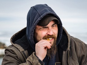 Jeff MacKinnon, an underwater treasure salvager, bites on a gold coin in this undated handout photo.