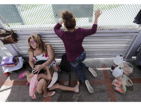 CORRECTS YEAR OF PHOTO TO 2018, NOT 2019 - FILE - In this June 24, 2018, file photo, immigrants from Honduras seeking asylum wait on the Gateway International Bridge, which connects the United States and Mexico, in Matamoros, Mexico. The Trump administration wants up to two years to find potentially thousands of children who were separated from their parents at the border before a judge halted the practice. The Justice Department said in a court filing late Friday, April 5, 2019, in San Diego that it will take at least a year to review the cases of 47,000 unaccompanied children taken in custody between July 1, 2017 and June 25, 2018.
