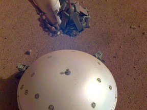 This photo made available by NASA on Tuesday, April 23, 2019 shows the InSight lander's domed wind and thermal shield which covers a seismometer on the 110th Martian day, or sol, of the mission. On Tuesday, the space agency announced the instrument picked up a gentle rumble, believed to be the first marsquake ever detected. (NASA/JPL-Caltech via AP)